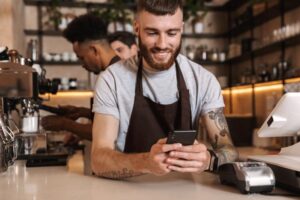 En-barista-kigger-paa-sin-telefon-og-indberetter-sygedagpenge.tablet